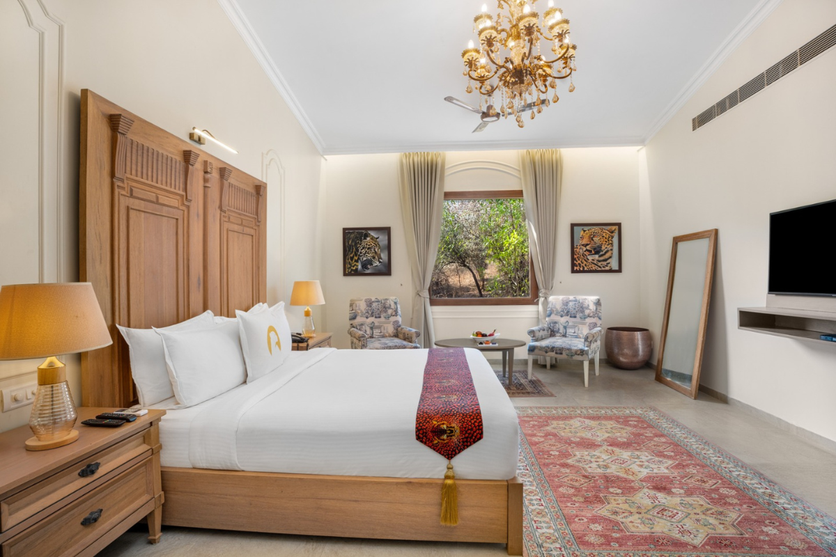 King-size bed with a wooden headboard, two nightstands, and warm lamps in a luxury hotel room.