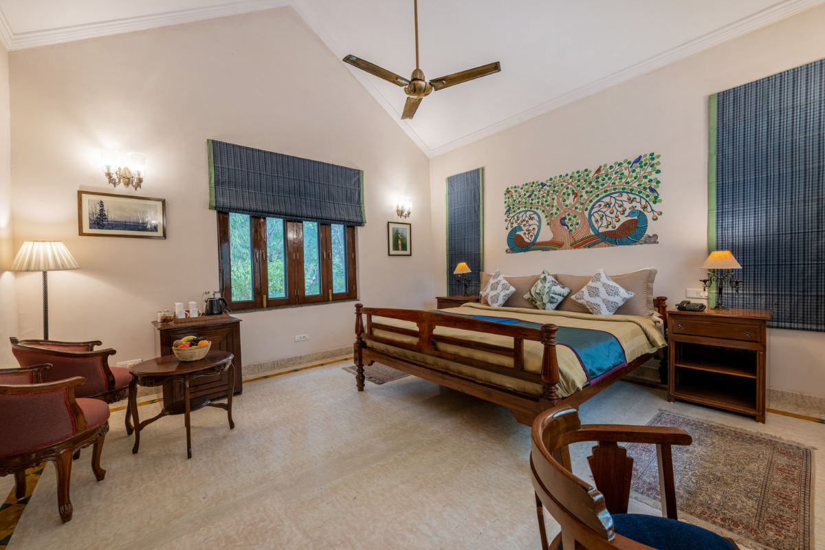 Hotel room with a large wooden bed, matching nightstands, and a colorful tree-and-bird mural above the headboard.