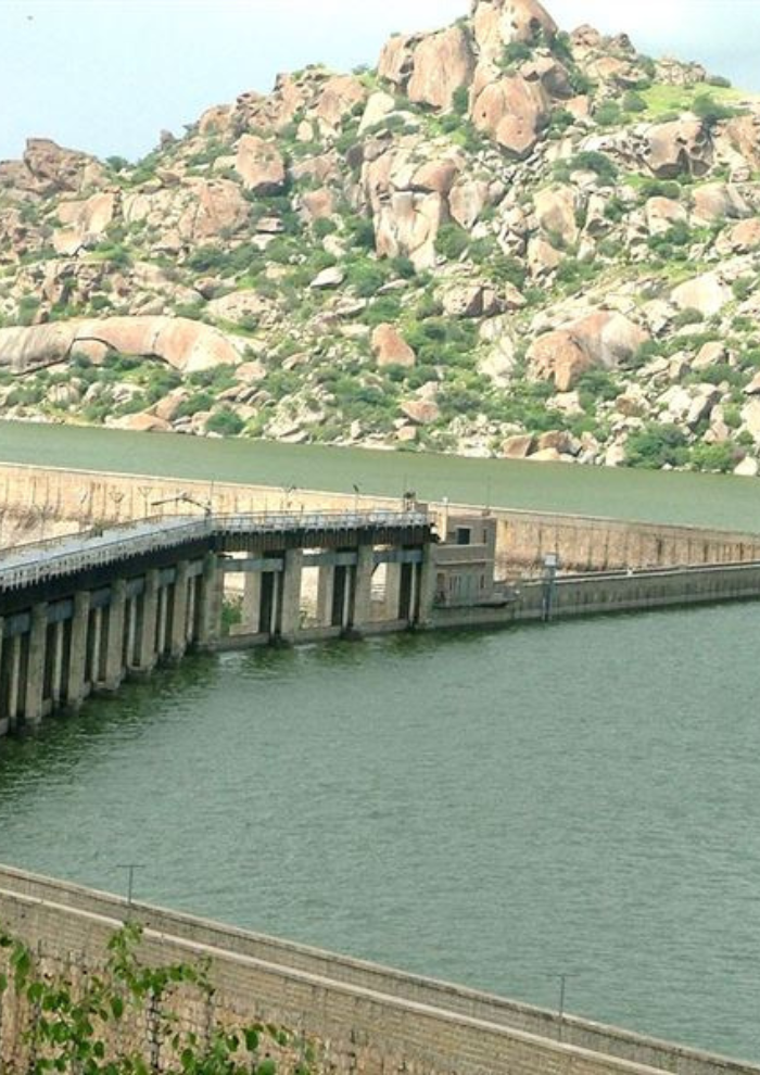 JAWAI DAM Concrete dam walkway extending into a green reservoir with rocky hillside in the background
