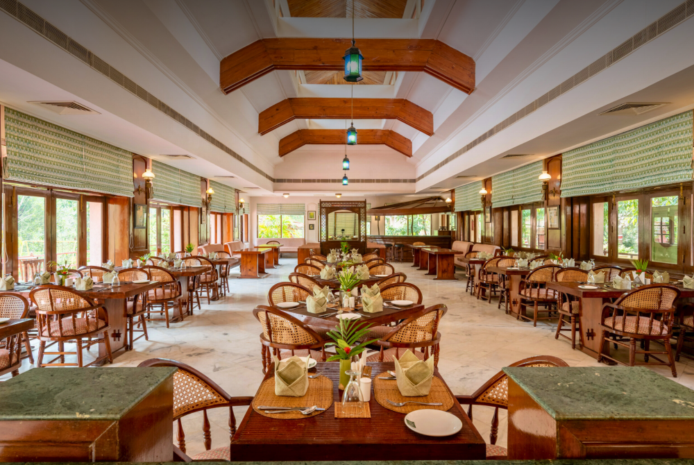 Spacious dining hall with wooden beams, lanterns, and many tables set for guests