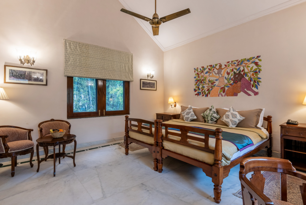 Warm hotel bedroom with a wooden bed, two nightstands, lamps, and a colorful wall mural on the right wall.