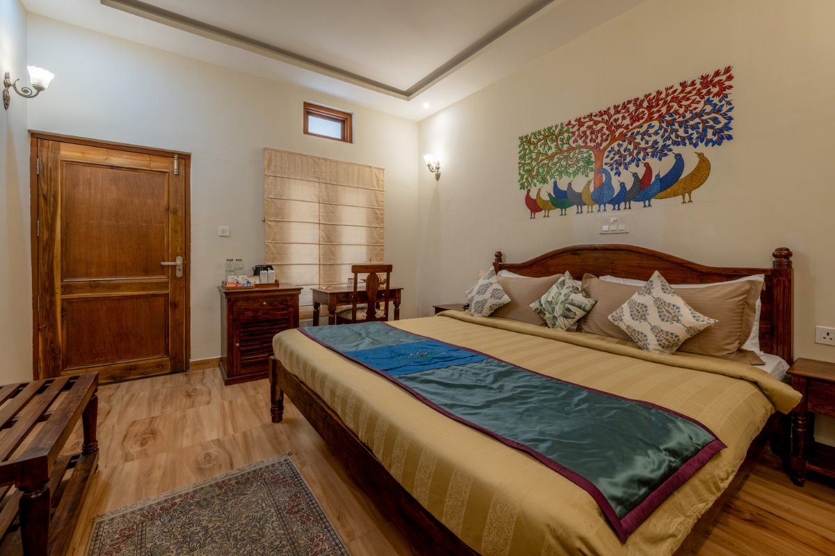Hotel room with a large wooden bed, beige bedding, and a colorful peacock mural on the wall.